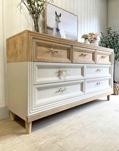 a white dresser with drawers and flowers on top