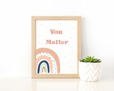 there is a small potted plant next to a framed print that says you matter