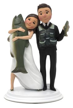 a wedding cake topper with a bride and groom holding a fish on it's back