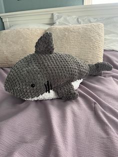 a stuffed shark laying on top of a bed