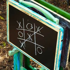 a chalkboard with tic - tacs written on it in front of some grass