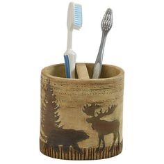 two toothbrushes in a wooden cup with moose and pine trees on the side