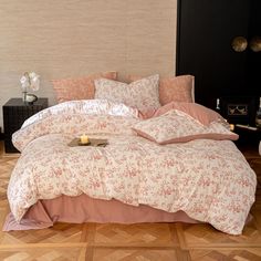 a bed with pink and white comforters in a room next to a lamp on a table