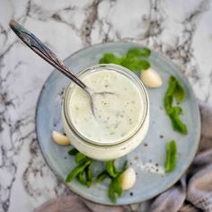 a glass jar filled with dressing sitting on top of a plate next to a spoon