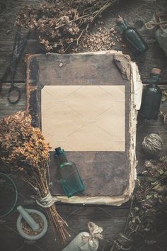 an old book and some dried flowers on a wooden table with other items around it