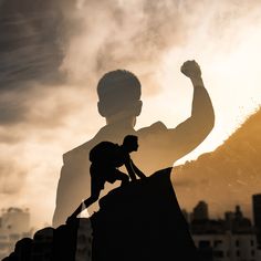 a man standing on top of a pile of dirt next to a tall building with his arm in the air