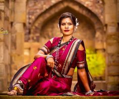 a woman sitting on the ground in a red sari