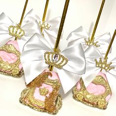 four pink and gold cake pops with white bows on them, sitting next to each other