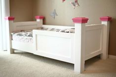 there is a white bed with pink posts on the headboard and foot board in this room