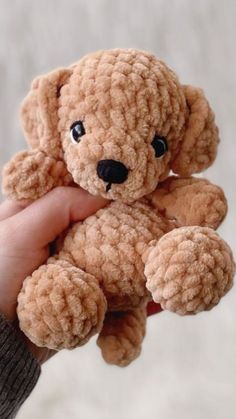 a person holding a small brown teddy bear in their left hand and wearing a sweater