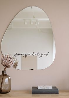 there is a mirror on the wall above a vase with a flower in it and an inscription that says, don't you look good?