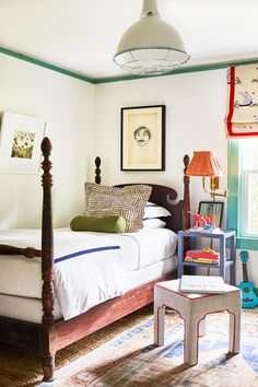 a bed room with a neatly made bed next to a window and a lamp hanging above it