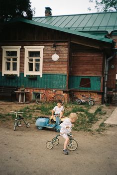 two small children playing on bikes in front of a house