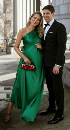 a man in a tuxedo standing next to a woman in a green dress