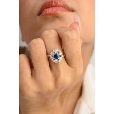 a close up of a person wearing a ring with an oval shaped blue and white diamond