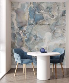 two blue chairs sitting at a white table in front of a wall with marble design