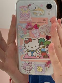 a person holding up a cell phone case with hello kitty stickers on the back