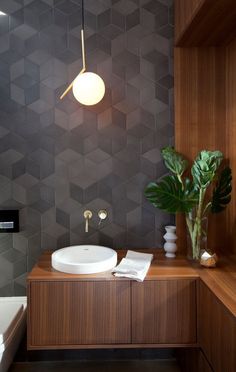 a bathroom with a sink, toilet and plant on the counter in front of it