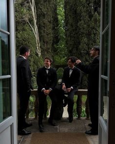 three men in tuxedos are sitting on a bench and talking to each other