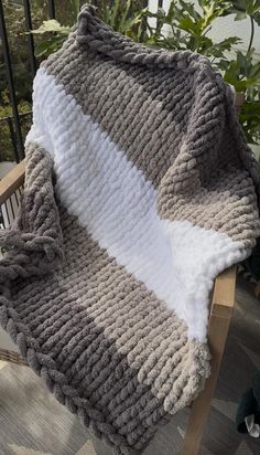 a blanket sitting on top of a wooden chair next to a potted green plant