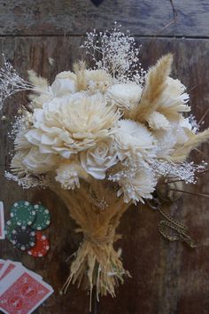 a bouquet of white flowers sitting on top of a wooden table next to playing cards