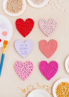 several heart shaped candys are on a table next to paper plates and paintbrushes