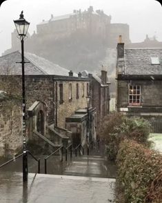 an alley way with stairs leading up to some buildings and a castle in the background