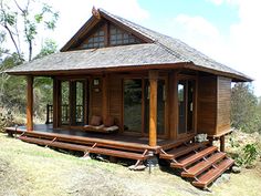 a small wooden cabin sitting on top of a grass covered field next to trees and bushes