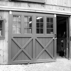 a black and white photo of a barn with an open garage door on the outside