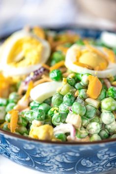 a blue bowl filled with peas, hard boiled eggs and other vegetables on top of it