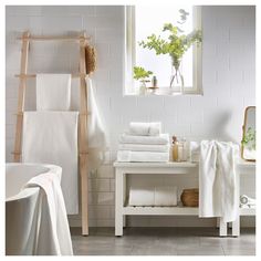 towels are stacked on a shelf next to a bathtub