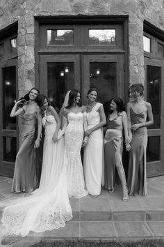 a group of women standing next to each other in front of a stone building with doors