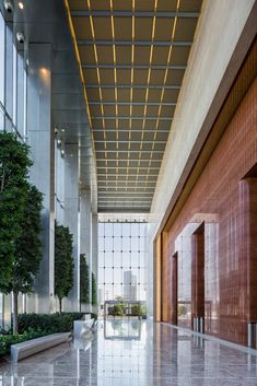 the inside of an office building with large windows and plants on either side of it