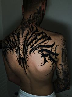 the back of a man with tattoos on his upper and lower part of his body