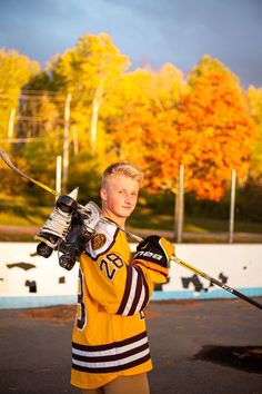 a young man is holding his hockey equipment