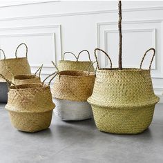 four woven baskets sitting on top of a floor next to a plant in a vase