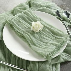 a white plate topped with green cloth next to silverware