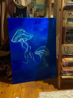 a painting of two jellyfish on a blue background in front of a rack of books