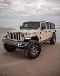 a white jeep parked on top of a sandy beach