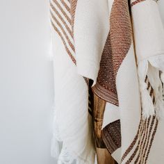 a white and brown blanket hanging up against a wall