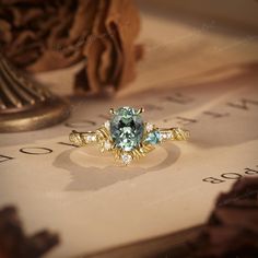 a ring with an aqua and white diamond in it sitting on top of a piece of paper