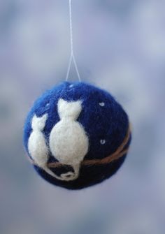 a blue and white ornament hanging from a string with two cats on it