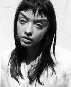 a black and white photo of a young woman with long hair wearing a collared shirt