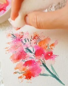 someone is painting flowers with watercolors on paper