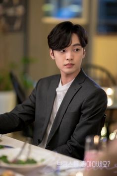 a young man sitting at a table with food in front of him and looking off to the side