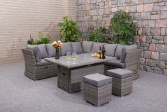 an outdoor patio furniture set with grey cushions and table, wine bottles and glasses on it