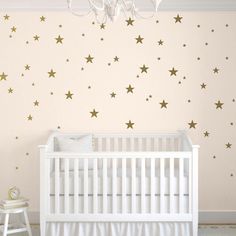 a baby's room with gold stars on the wall and a chandelier