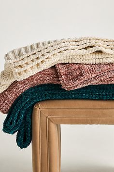 a stack of blankets sitting on top of a wooden bench