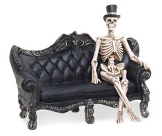 a skeleton sitting on top of a black couch