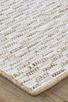 an area rug with white and brown stripes on the top, in front of a wooden floor